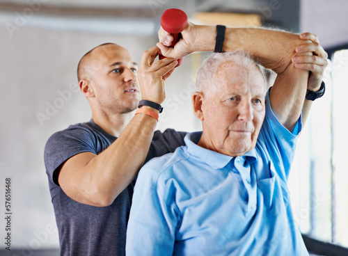 Working his way back to his healthy self. Shot of a physiotherapist helping a senior man with weights.