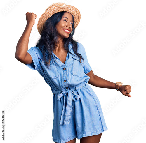 Fototapeta Young indian girl wearing summer hat dancing happy and cheerful, smiling moving