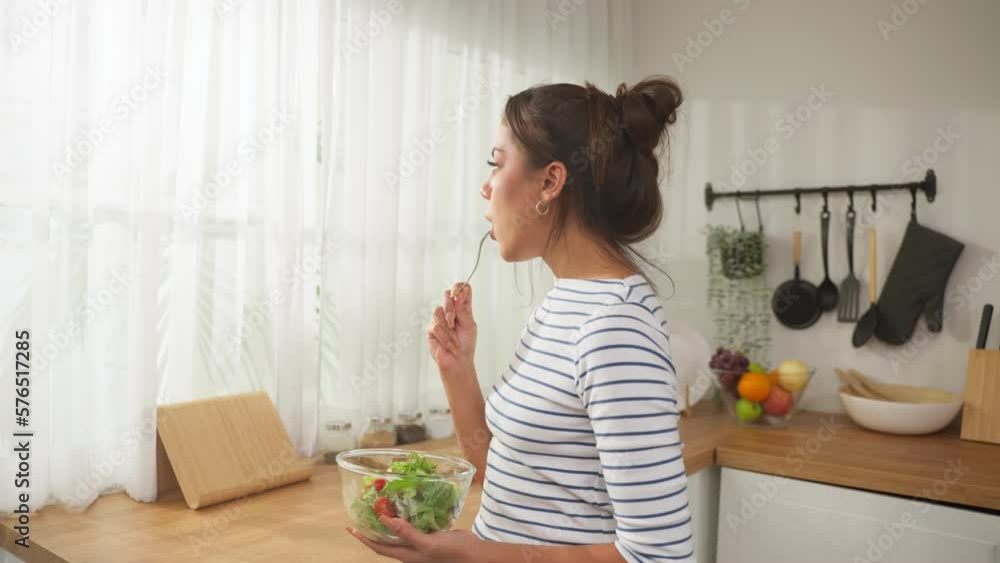 Caucasian young woman eating healthy green salad in kitchen at home. Caucasian young woman eating healthy green salad in kitchen at home.