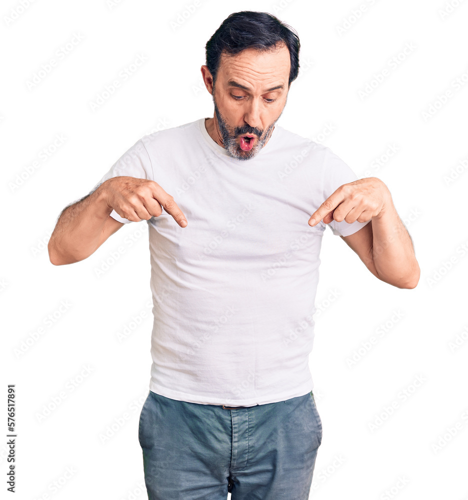 Middle age handsome man wearing casual t-shirt pointing down with fingers showing advertisement, surprised face and open mouth Middle age handsome man wearing casual t-shirt pointing down with fingers showing advertisement, surprised face and open mouth