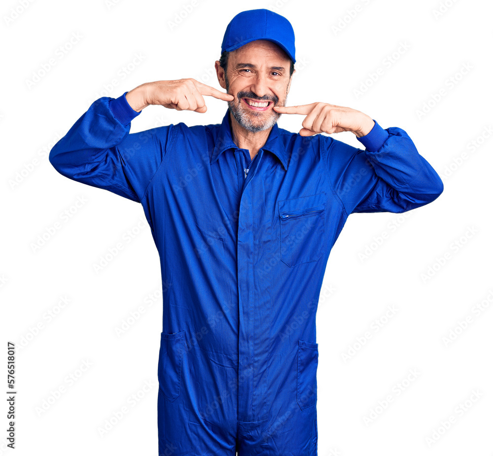 Middle age handsome man wearing mechanic uniform smiling cheerful showing and pointing with fingers teeth and mouth. dental health concept.