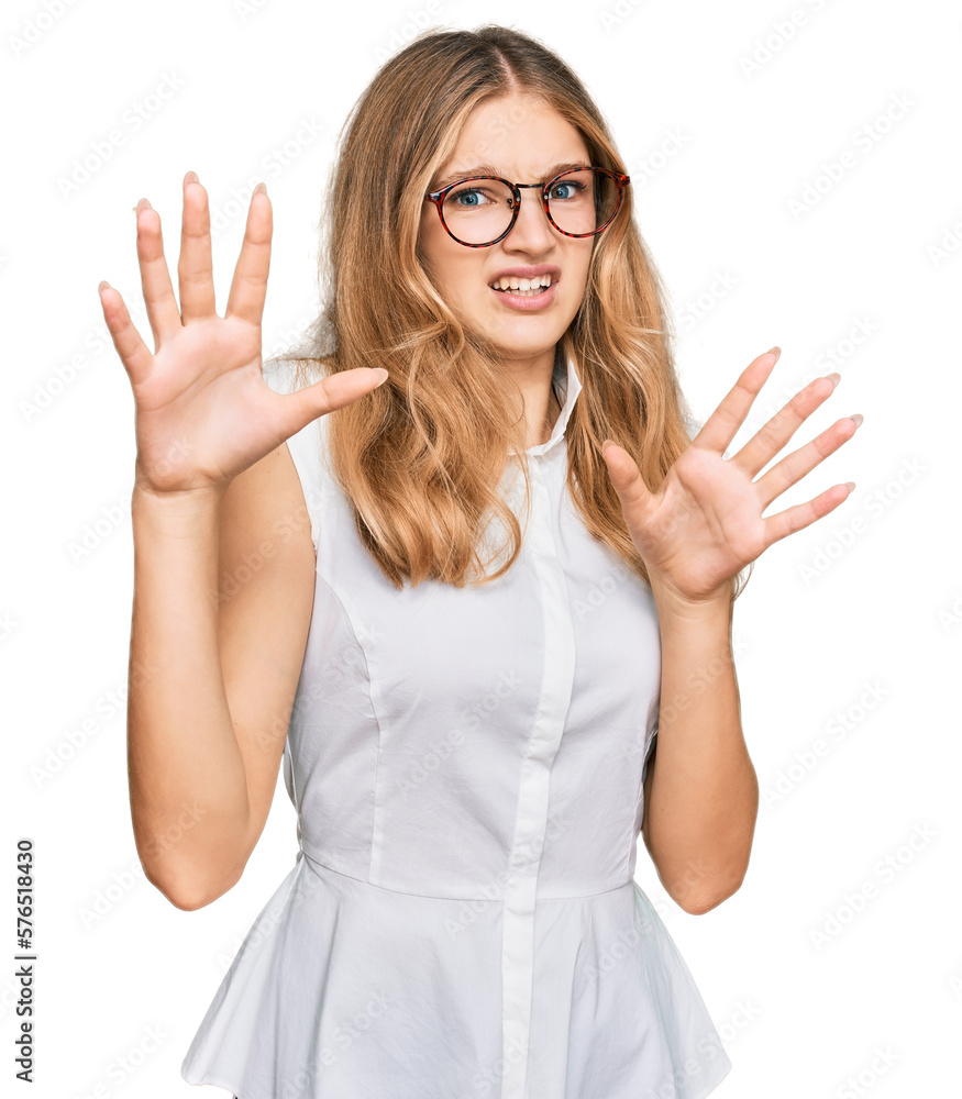 Beautiful young caucasian girl wearing casual clothes and glasses afraid and terrified with fear expression stop gesture with hands, shouting in shock. panic concept. Beautiful young caucasian girl wearing casual clothes and glasses afraid and terrified with fear expression stop gesture with hands, shouting in shock. panic concept.