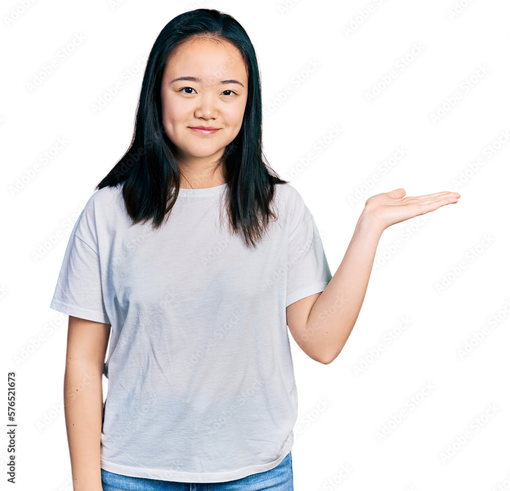 Young chinese woman wearing casual white t shirt smiling cheerful presenting and pointing with palm of hand looking at the camera. Young chinese woman wearing casual white t shirt smiling cheerful presenting and pointing with palm of hand looking at the camera.