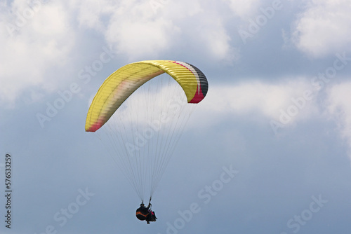 Tandem Paraglider flying in a cloudy sky