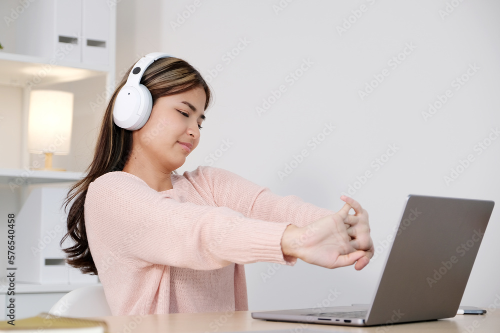 Young asian woman with headphones stretching for relax after working Young asian woman with headphones stretching for relax after working