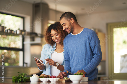 Using a step by step online recipe. Shot of a happy young couple using a digital tablet while preparing a healthy meal together at home.