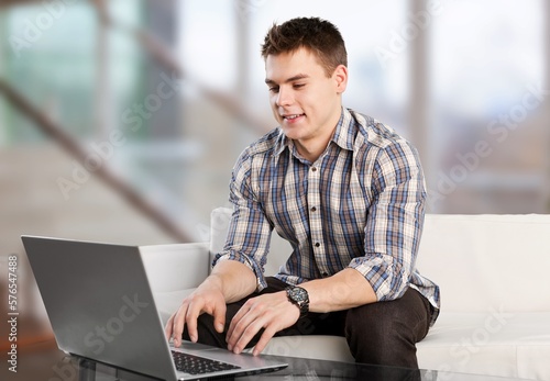 Young man sitting on sofa with laptop computer