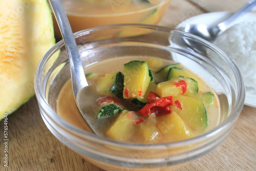 Indonesian food called lodeh labu muda made of young pumpkin, chilli, onion,garlic and coconut milk in a glass bowl on the table photo