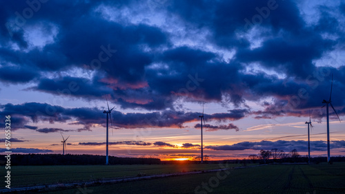 Sonnenuntergang auf einem Feld mit Windkraftr  dern