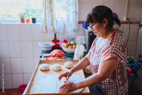 Portrait of an elderly latin woman cooking homemade bread in her kitchen photo