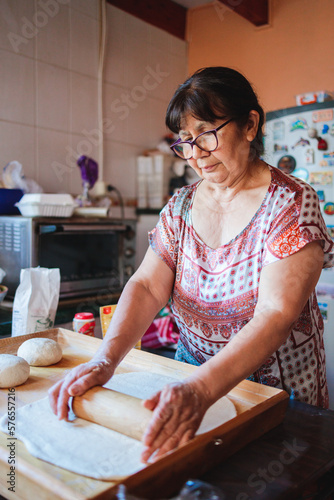 Portrait of an senior hispanic woman cooking homemade bread in her kitchen photo