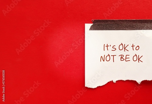 Torn note paper stick on red copy space background with text written IT\'S OK TO NOT BE OK, means feelings and emotions expressing  valid no matter what, it is normal to say you are not okay