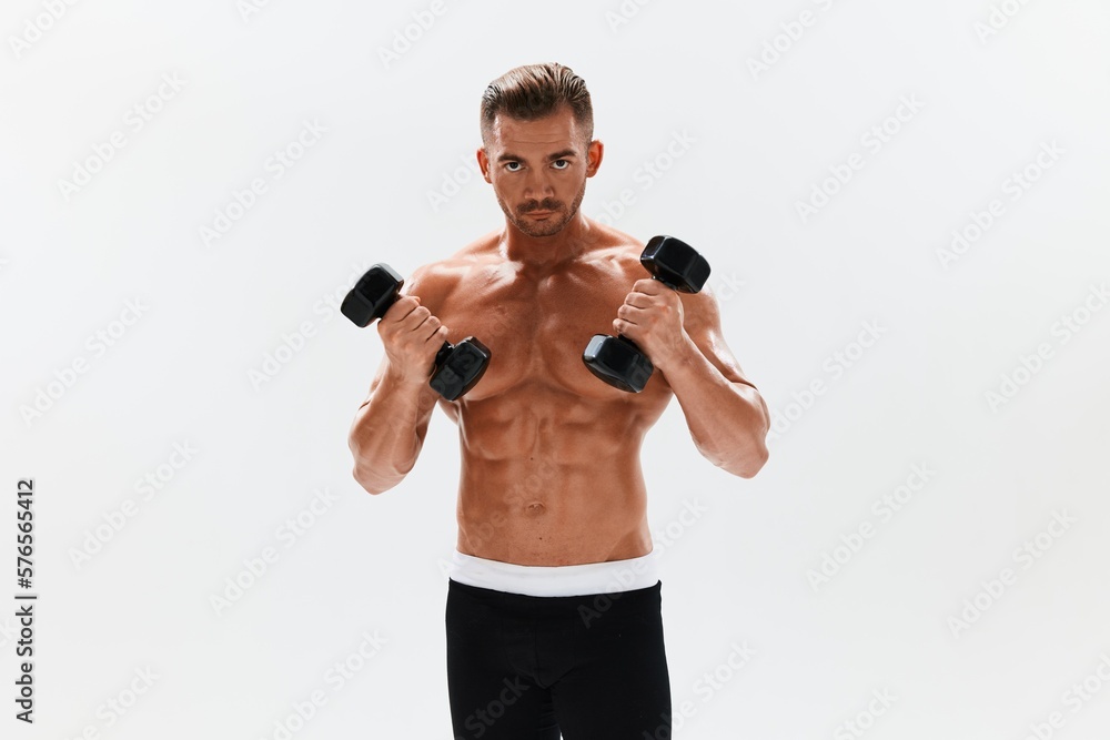 Man athletic body bodybuilder posing with dumbbells with naked torso abs full-length in the background, fitness class. Advertising, sports, active lifestyle, competition, challenge concept. Man athletic body bodybuilder posing with dumbbells with naked torso abs full-length in the background, fitness class. Advertising, sports, active lifestyle, competition, challenge concept.