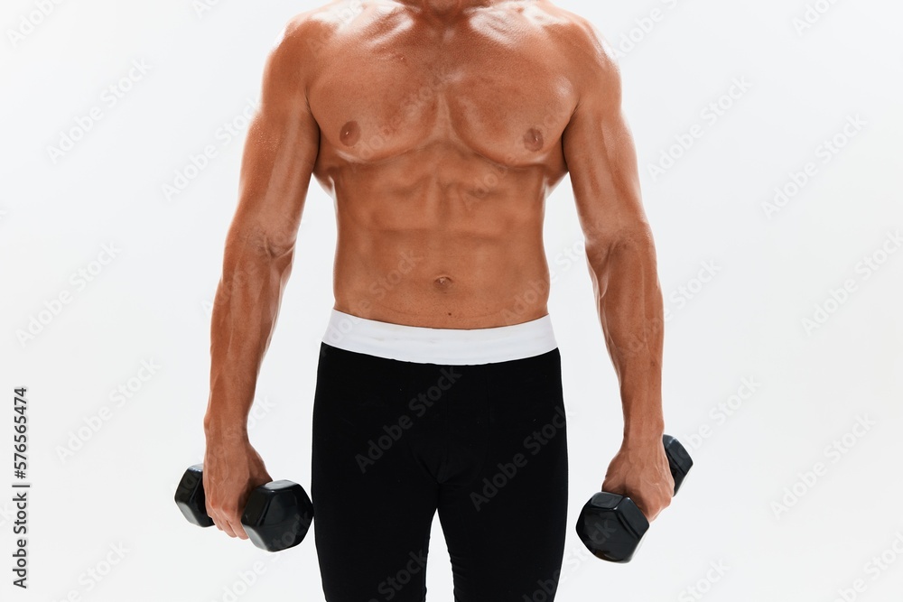 Man athletic body bodybuilder posing with dumbbells with naked torso abs full-length in the background, fitness class. Advertising, sports, active lifestyle, competition, challenge concept. Man athletic body bodybuilder posing with dumbbells with naked torso abs full-length in the background, fitness class. Advertising, sports, active lifestyle, competition, challenge concept.