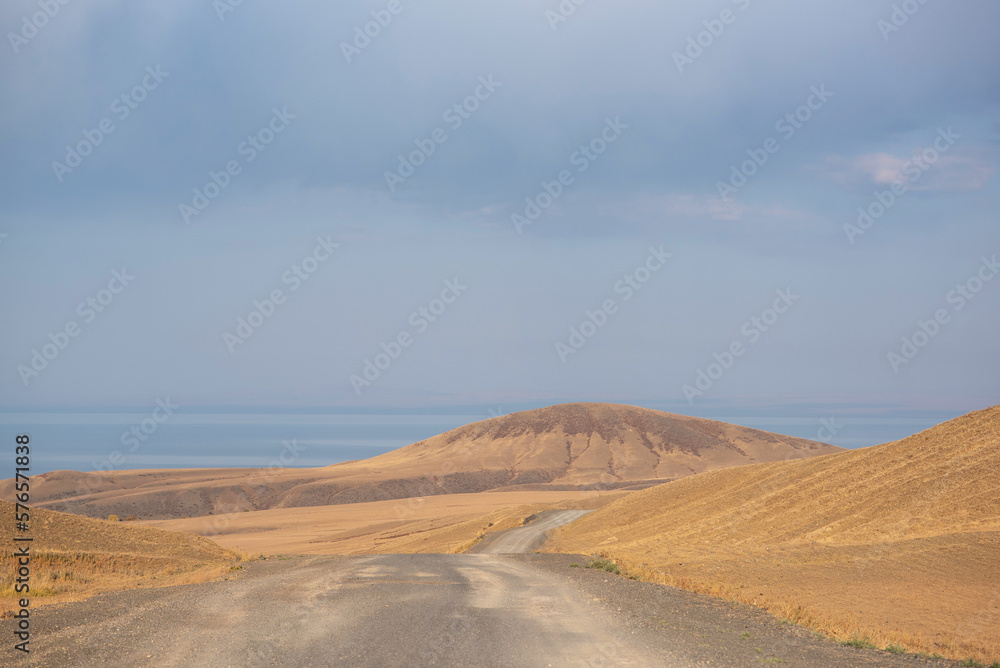 Unusual desert hilly landscape with a bright cloudy sky. Autumn in the remote foothills of northern China. Dry grass and hills. Exploring new places, traveling to distant locations. Unusual desert hilly landscape with a bright cloudy sky. Autumn in the remote foothills of northern China. Dry grass and hills. Exploring new places, traveling to distant locations.