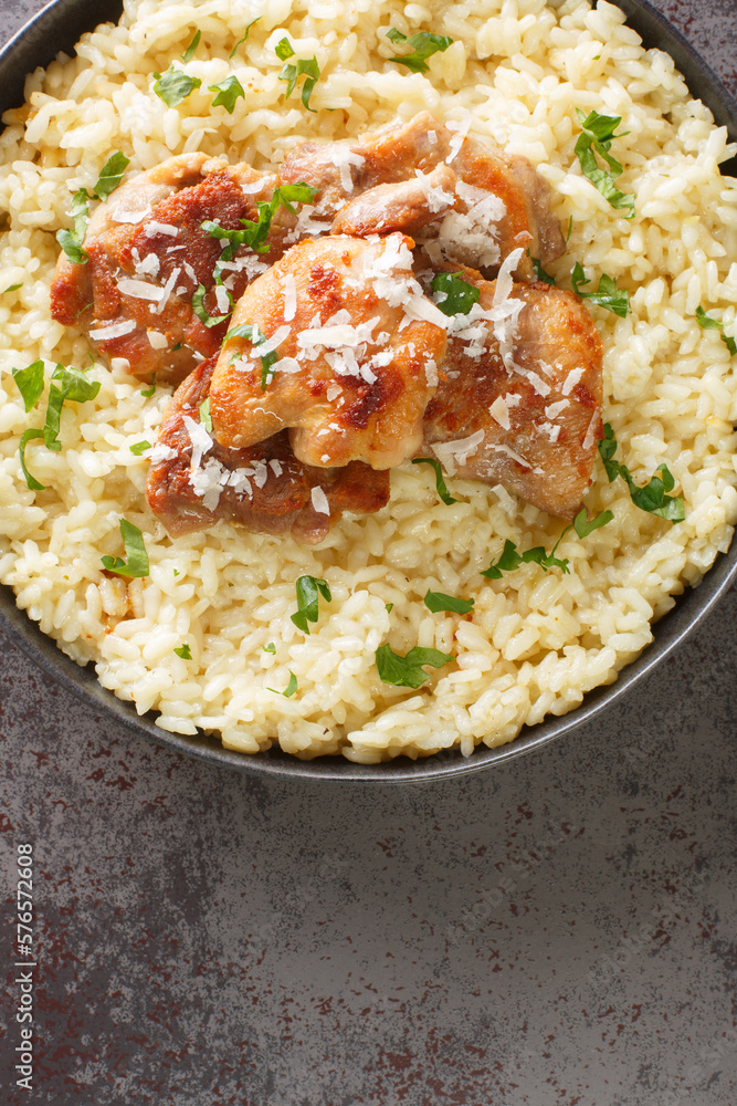 Traditional Italian dish Risotto with chicken, garlic, parmesan cheese and herbs closeup on the plate on the table. Vertical top view from above Traditional Italian dish Risotto with chicken, garlic, parmesan cheese and herbs closeup on the plate on the table. Vertical top view from above