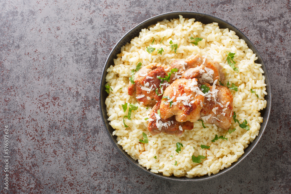 Homemade creamy rice cooked with white wine, broth, parmesan and garlic served with fried chicken close-up in a plate on the table. Horizontal top view from above