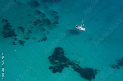 Sailing boat anchored on transparent blue water top view
