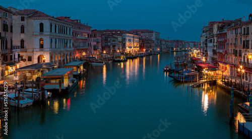 A canal in venice at night with lights on the buildings and boats on the water.