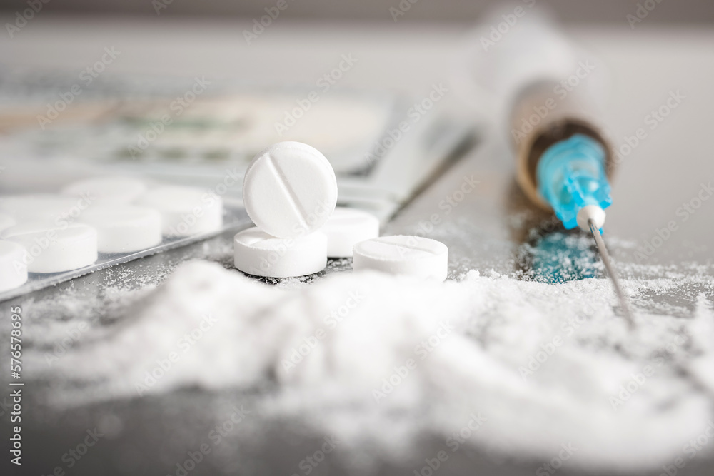 White pills, drugs or medical treatment, cocaine or heroin white powder, syringe with a dose and us dollar cash. Drug abuse and addiction concept White pills, drugs or medical treatment, cocaine or heroin white powder, syringe with a dose and us dollar cash. Drug abuse and addiction concept