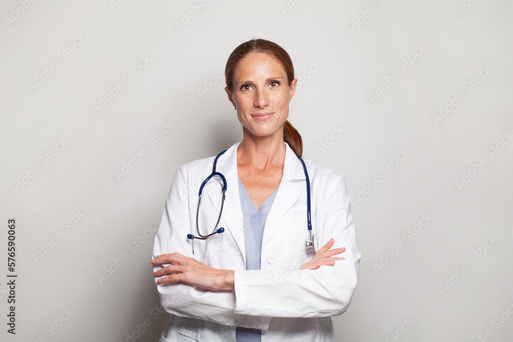 Smiling physician doctor medical worker or nurse mid adult woman with stethoscope standing with crossed arms against grey studio wall banner background Smiling physician doctor medical worker or nurse mid adult woman with stethoscope standing with crossed arms against grey studio wall banner background