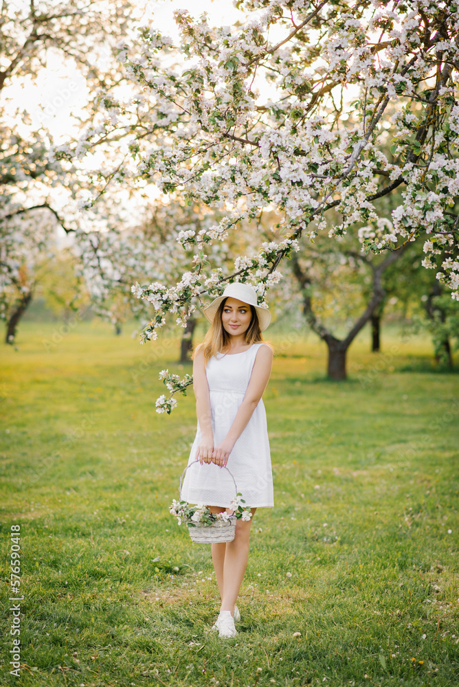 A young happy woman walks through an apple orchard among spring white flowers A young happy woman walks through an apple orchard among spring white flowers