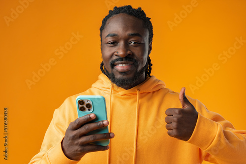 Portrait of handsome african man using his mobile agaist yellow background