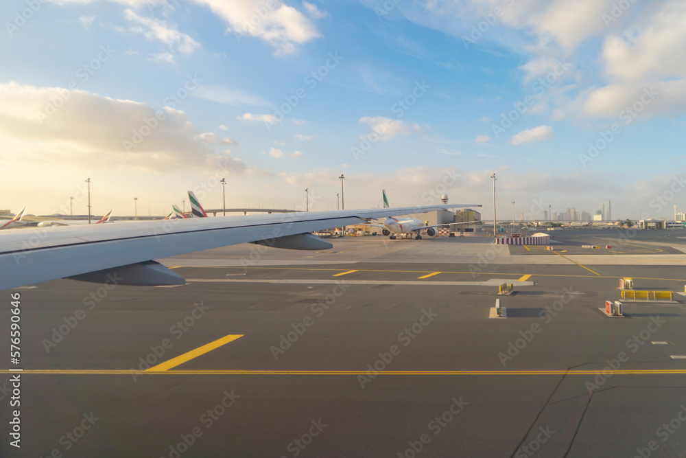 Fototapeta premium Wing of an airplane jet flying and landing with buildings view in urban city from window at runway in the airport. Traveling and transportation concept.