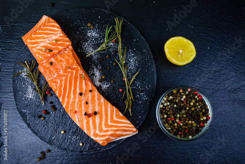 Raw fillet of salmon fish and spices on a slate board. Top view