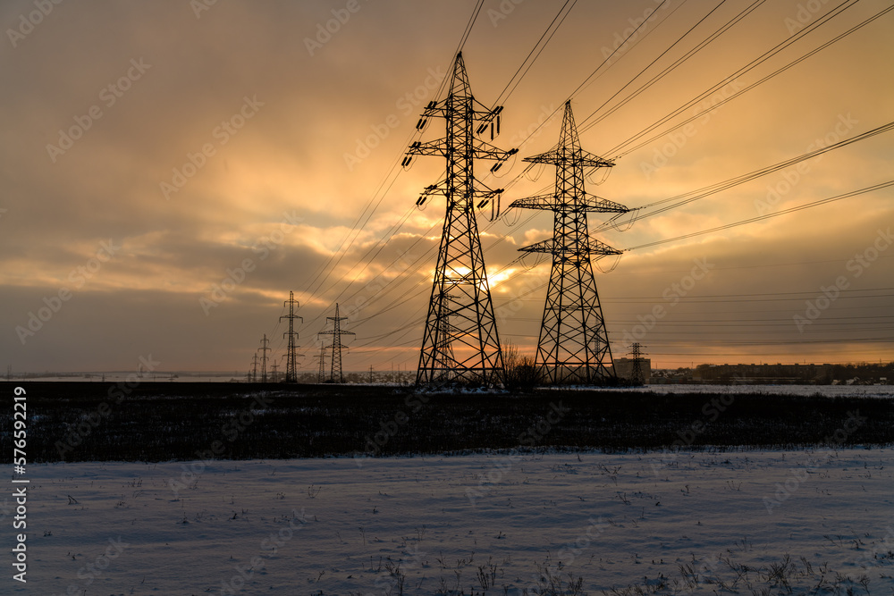 High voltage power line in a field at sunset on winter