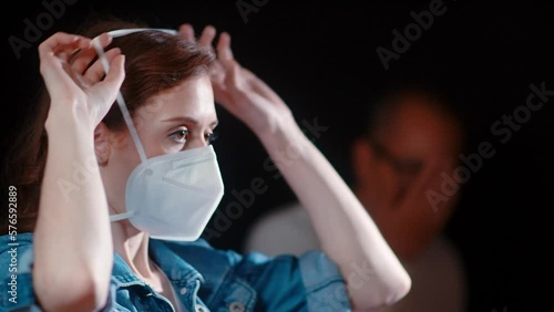 (Camera: ARRI ALEXA, real time) A young caucasian woman puts on her n95 mask while a man is coughing in the background. For more variations of this clip, check out this seller's other videos. photo