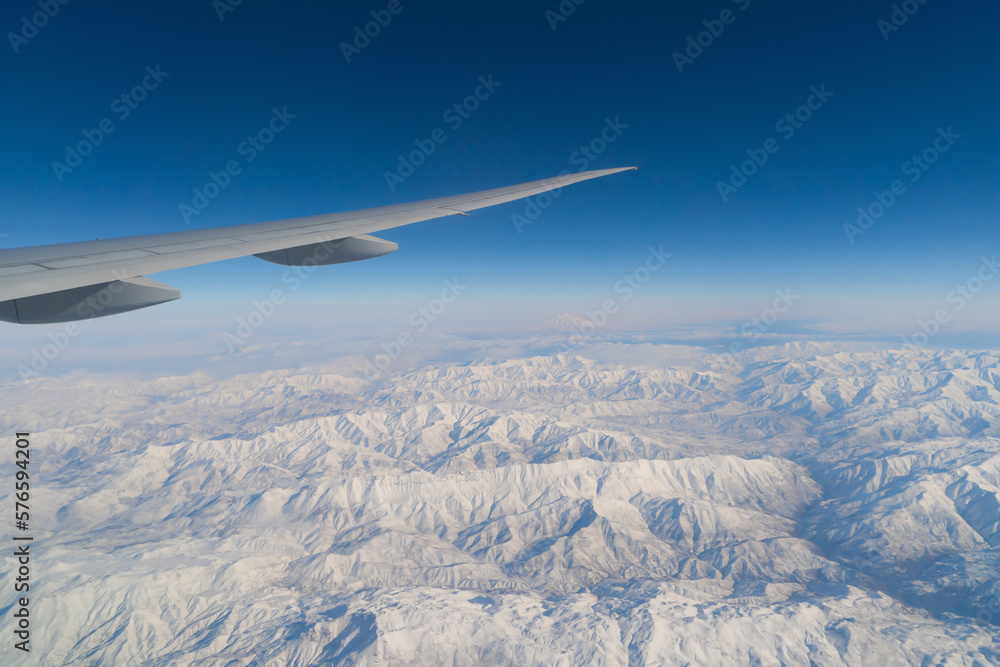 Wing of an airplane jet flying above clouds with blue sky from the window in traveling and transportation concept. Nature landscape background. Wing of an airplane jet flying above clouds with blue sky from the window in traveling and transportation concept. Nature landscape background.
