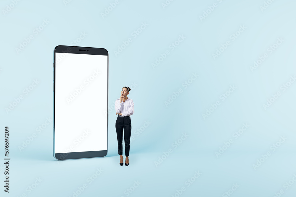 Online, digital and mobile application concept with pensive woman near huge modern smartphone with blank white screen and space for web design or landing page on light blue wall background, mockup Online, digital and mobile application concept with pensive woman near huge modern smartphone with blank white screen and space for web design or landing page on light blue wall background, mockup