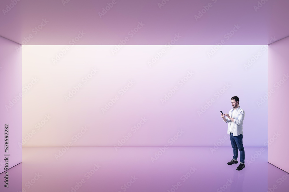 Perspective view on young man using smartphone in empty spacious area with purple shadows wall space background for your product or car presentation, mockup Perspective view on young man using smartphone in empty spacious area with purple shadows wall space background for your product or car presentation, mockup
