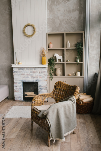 Wicker armchair with a plaid near the fireplace in a country house in the Scandinavian-style living room
