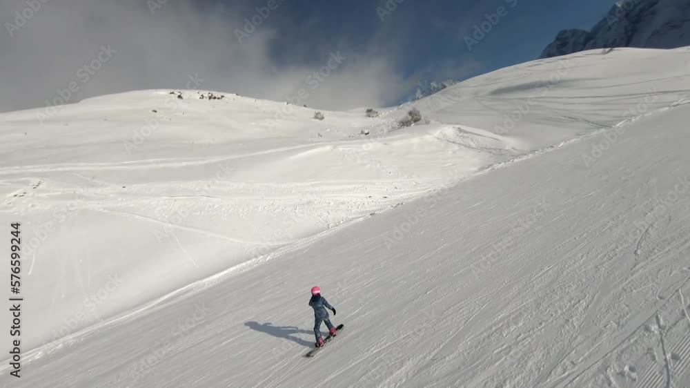 A girl goes down on a snowboard in a pink helmet in winter there is a lot of snow in the big mountains shooting on an FPV drone Mount Dombay
A girl goes down on a snowboard in a pink helmet in winter there is a lot of snow in the big mountains shooting on an FPV drone Mount Dombay