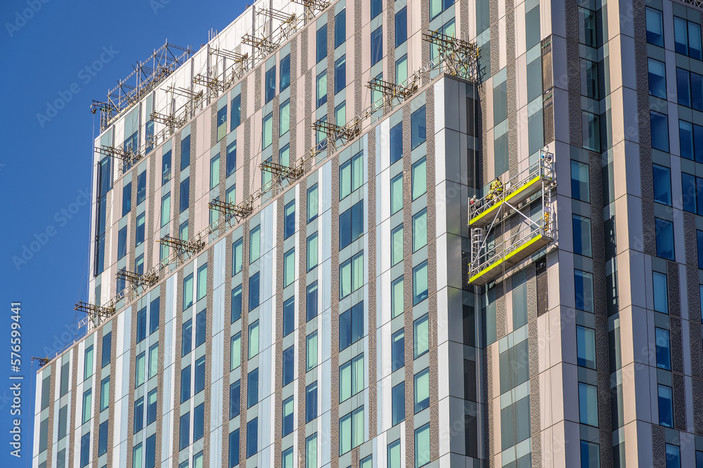 Fototapeta premium Construction workers inspecting / installing cladding on an apartment building in London, England