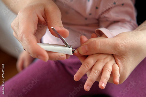 Mother use Nail Trimmer with baby hand. Mom cutting tiny fingernails. Baby care concept. How to successfully clip your baby's nails. Closeup. Newborn hygiene. Clipping Child's Nails. Front view.