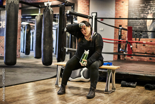 A female boxer taking a rest during her workout at the boxing gym. photo