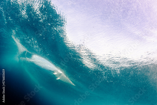 Underwater point of view of a man surfing on a surfboard photo