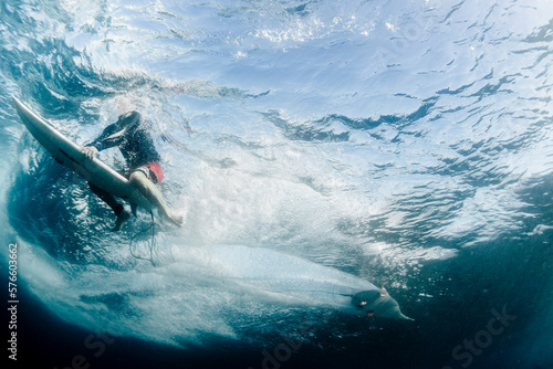 Underwater point of view of a man surfing on a surfboard photo
