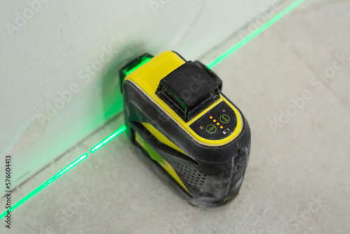 Construction laser level and the hands of a worker. Builder measures the level. Repair concept.
