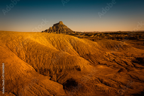 A stark desert landscape with a formation in the distance.