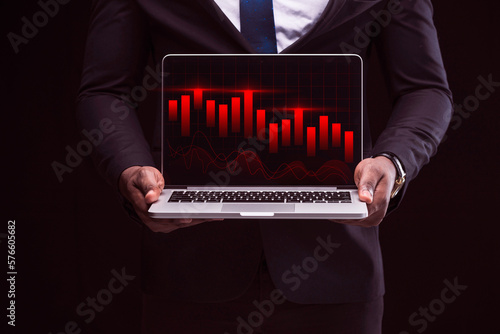 Businessman showing bear market stock chart analytics in a laptop, holding a laptop in front, Stock, Cryptocurrency chart trader, trading, investment. Trend of graph.