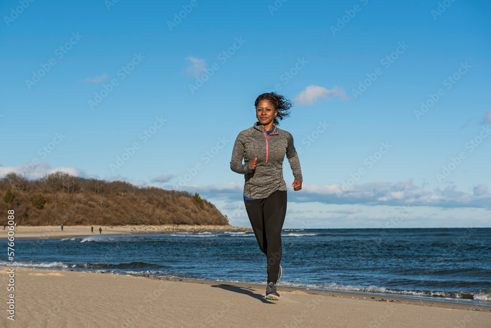 Woman jogging on coastal beach, Newburyport, Massachusetts, USA Woman jogging on coastal beach, Newburyport, Massachusetts, USA
