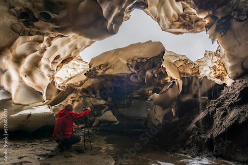 Photographer with tripod in snow cave, Yelizovo, Kamchatka Peninsula, Russia photo