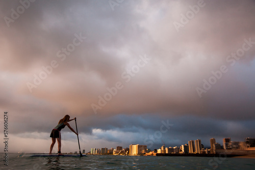 Silhouette of woman paddleboarding at sunset at Kaimana Beach, Waikiki, Honolulu, Oahu, Hawaii, USA photo