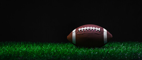 American football on green grass, on black background. Horizontal sport theme poster, greeting cards, headers, website and app.