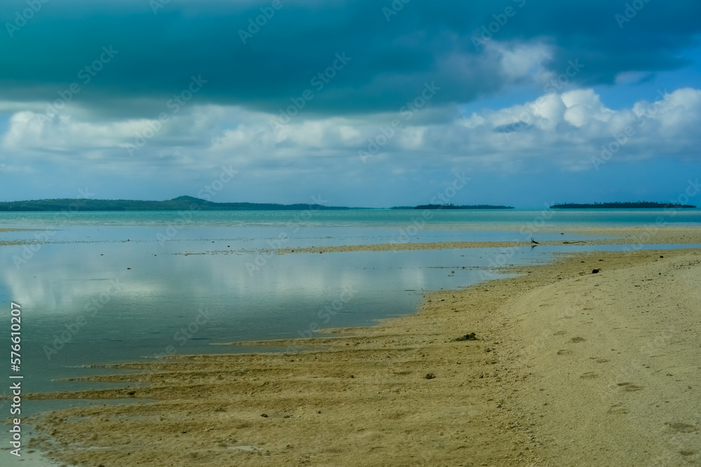 Sun illuminated beach below dark storm clouds .