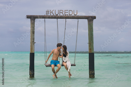 A young couple is swinging on a swing on a tropical beach in the Maldives. Summer holidays